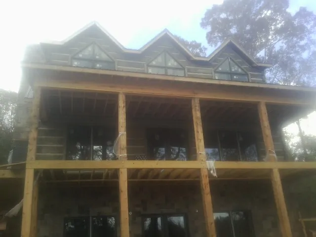 Dormers and porch framing on a large log home under construction — Roof Coating work by our crew in Hallsville