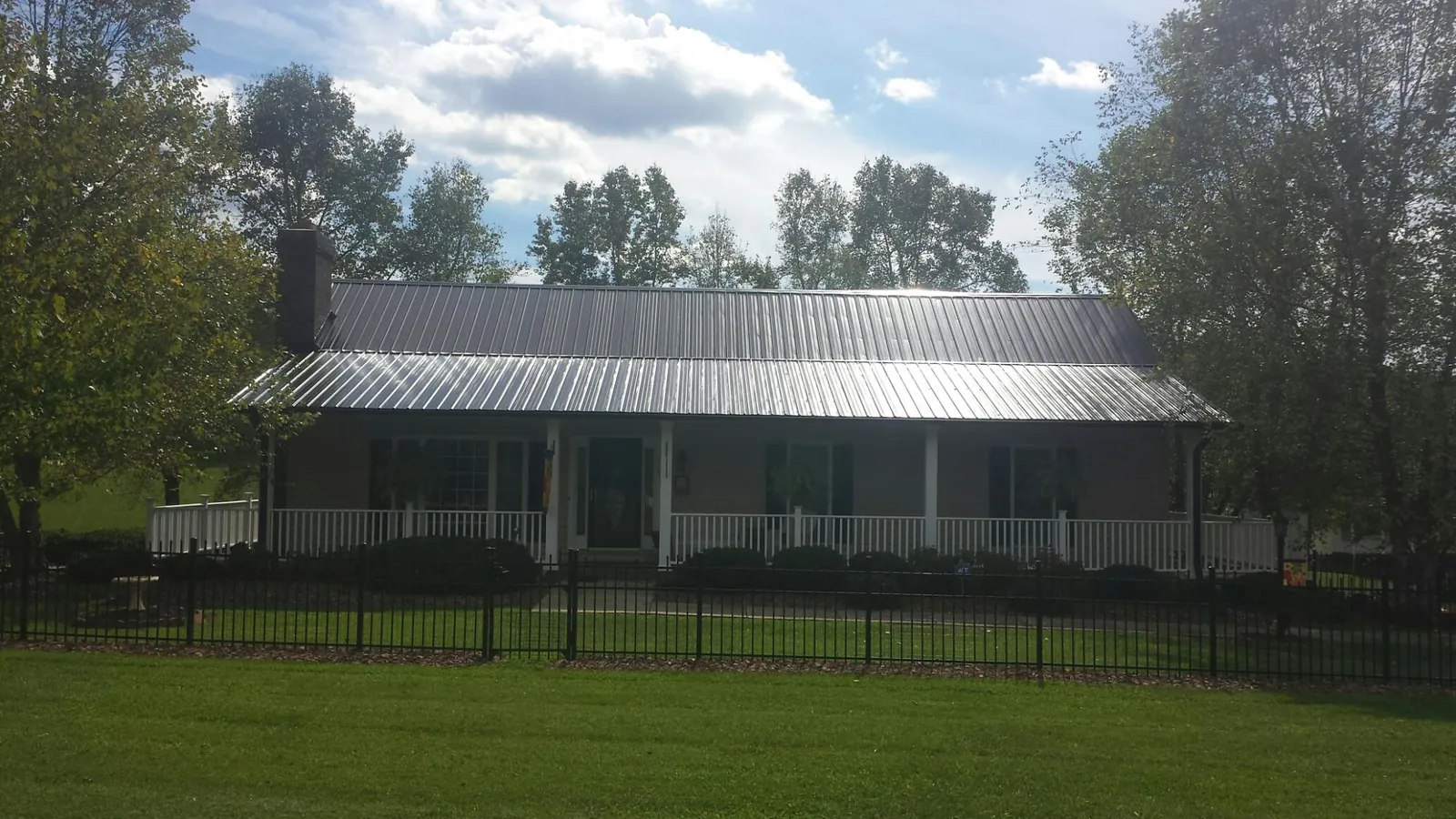 Gray metal roof on a brick ranch with a full width front porch — Gutter Guard Installation work by our crew in Hallsville