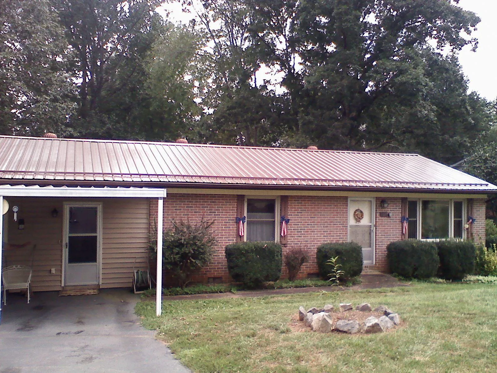 Bronze metal roof and carport on a brick ranch home — Roof Repair work by our crew in Hallsville