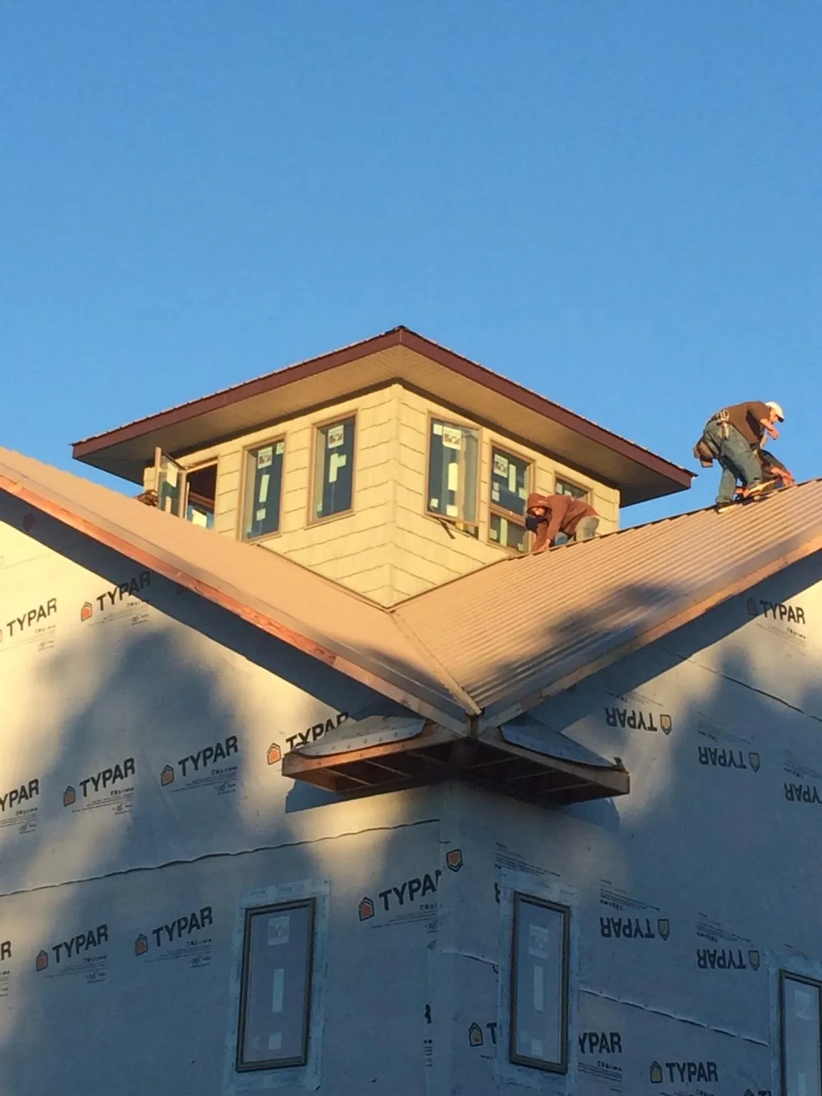 Roofers working around a rooftop cupola on a new metal roof at sunset — Roof Waterproofing in Hallsville by Roofing Brothers